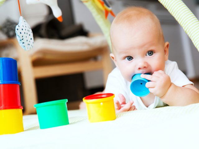 Baby playing with colorful toys at home. Happy 6 months old baby child playing and discovery.